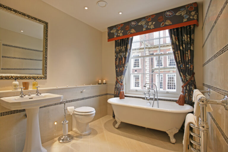 a bathroom with a tub, toilet, sink and window
